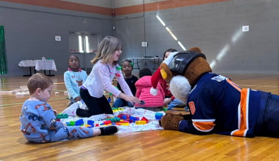 Stomper playing with kids on gym floor