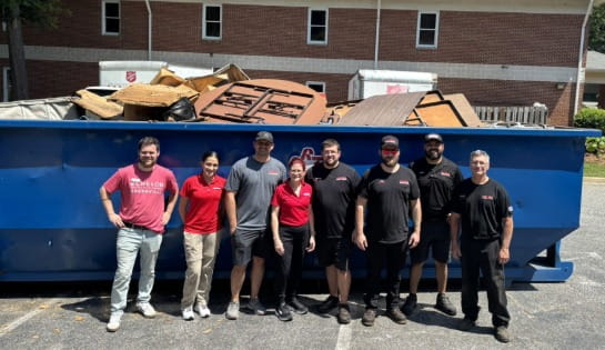 Carolina Handling team in front of a dumpster after lean transformation. 