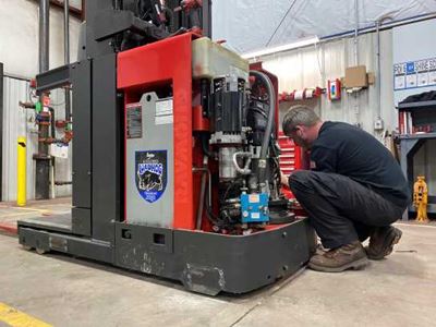 Technician working on repairing a red raymond forklift
