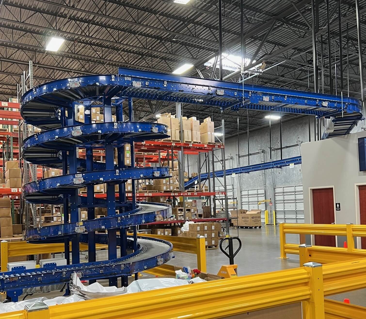 A motor-driven roller (MDR) spiral turn lifts packages to an overhead conveyor that delivers them to shipping.