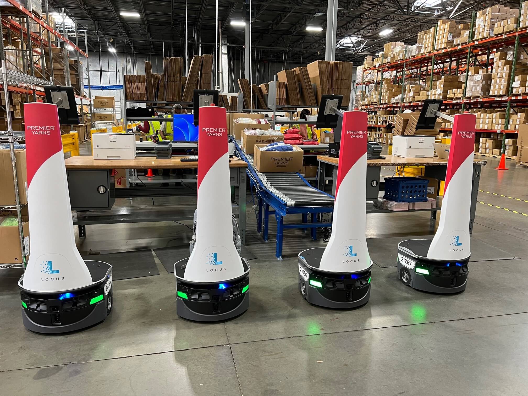 Locus mobile robots deliver orders to induction where they are checked, packed and labeled at new packing stations, then placed on the conveyor for delivery to shipping.